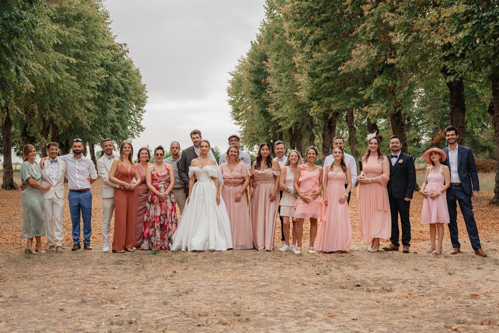 Les mariés et leurs proches réunis dans l'allée d'arbres du Château Le Sallay