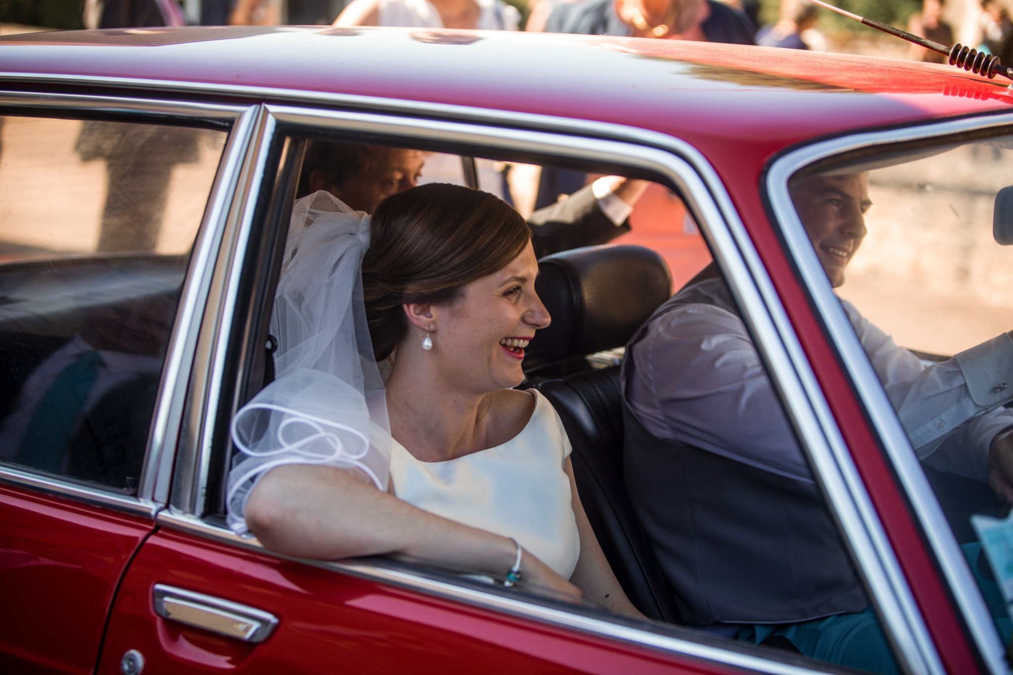 La mariée riant à l'arrière d'une voiture ancienne au Château de Planchevienne
