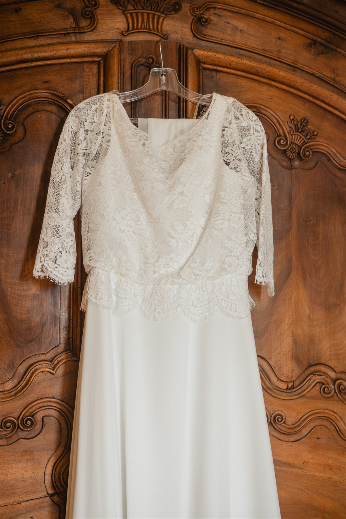 Robe de mariée en dentelle suspendue à une armoire ancienne