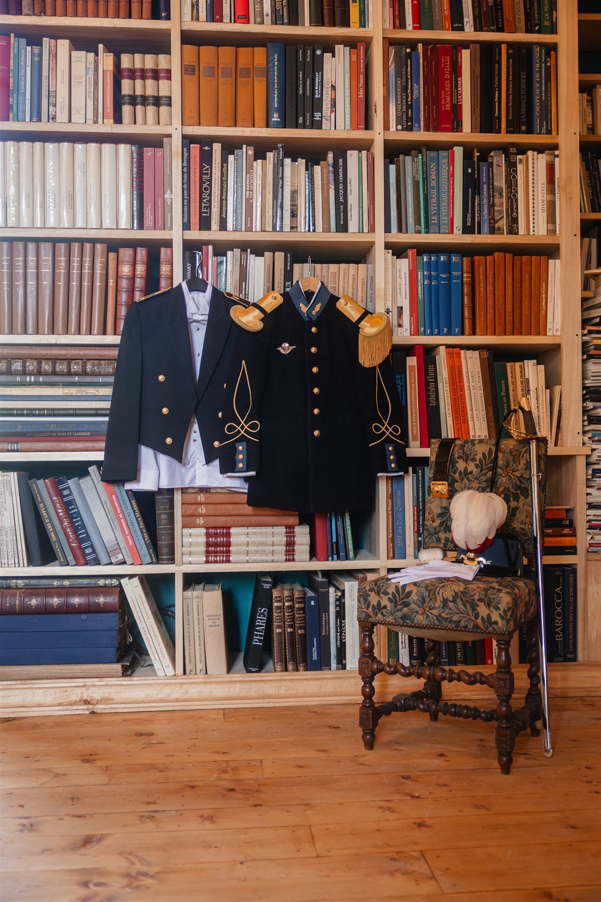 Uniformes de cérémonie suspendus devant les rayonnages de la bibliothèque du Château des Bordes