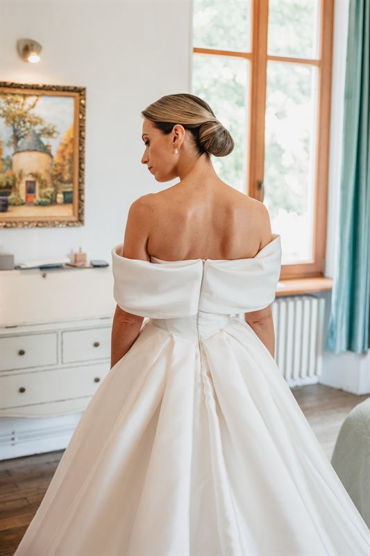 Mariée de dos devant une fenêtre, robe structurée