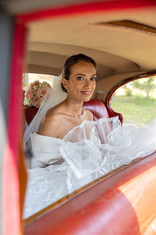 Mariée photographiée depuis une voiture ancienne