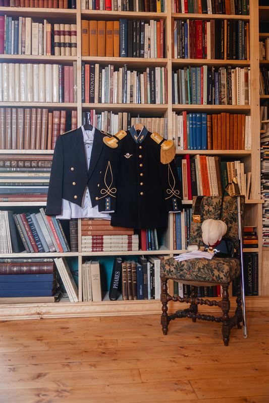 Ceremonial uniforms hanging against a library wall