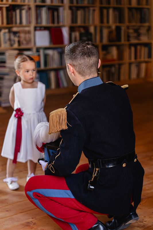 The groom kneeling before a flower girl