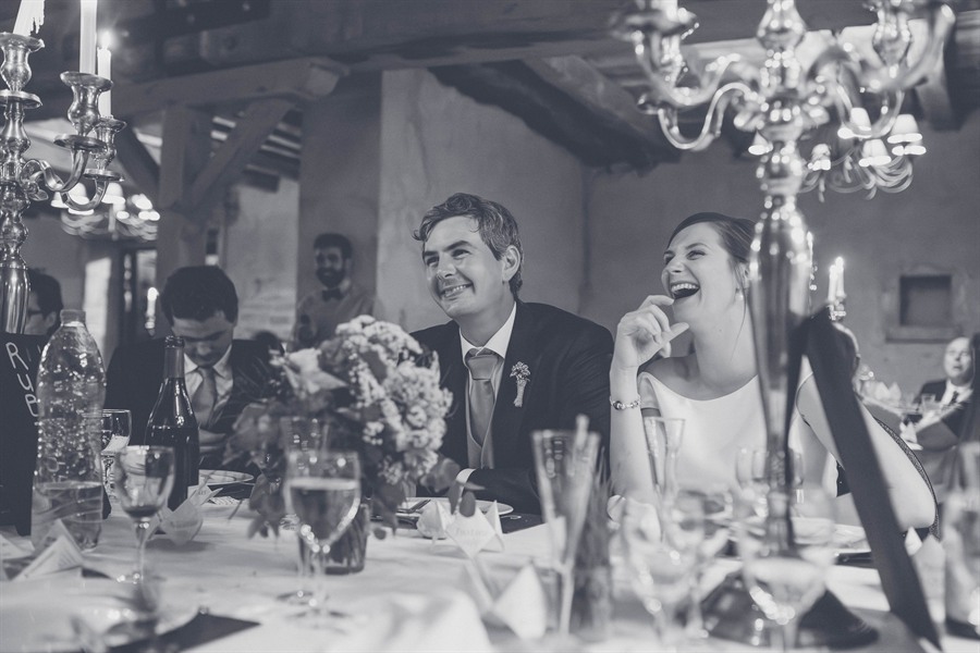 Les mariés riant à la table d’honneur, chandeliers et bouquet, noir et blanc