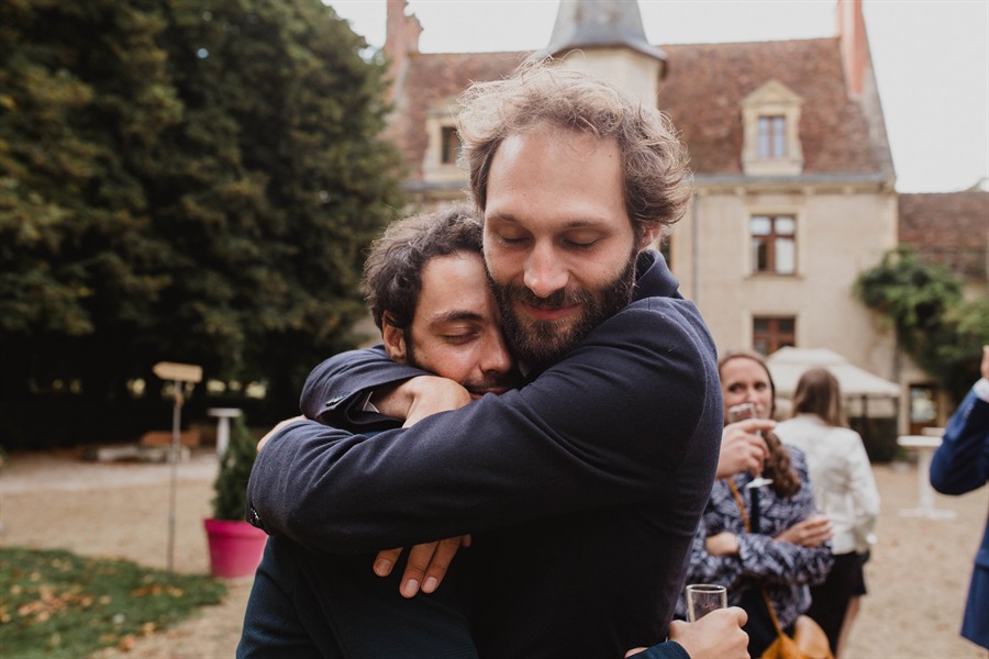 Accolade émue entre deux invités devant le château